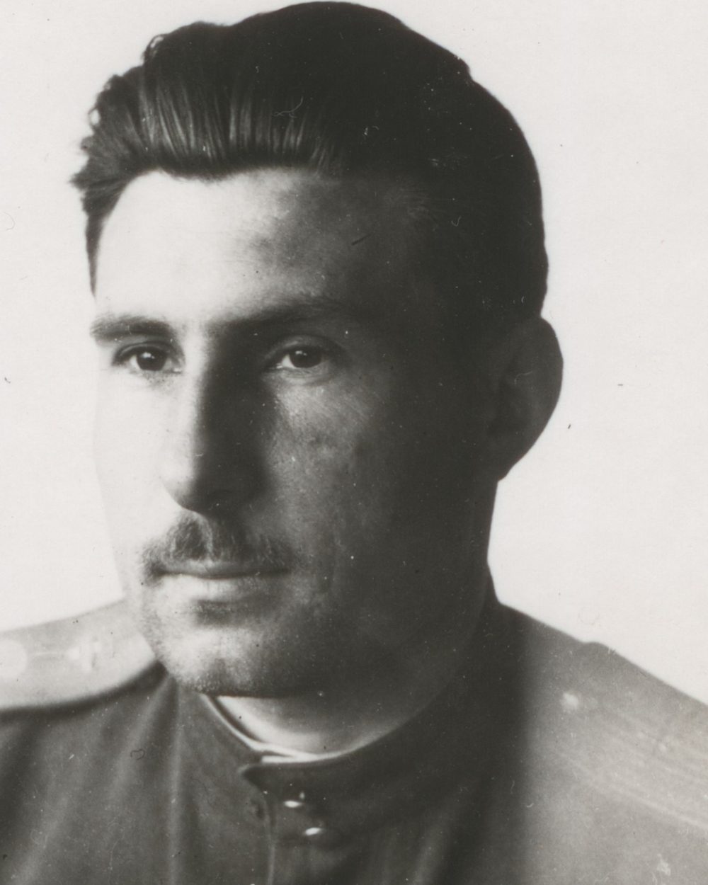 A soft, low-contrast black and white photograph of a wartime pilot.